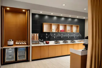 a kitchen with brown cabinets and a black wall at SpringHill Suites by Marriot Troy Dayton in Troy