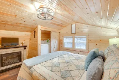 a log cabin bedroom with a bed and a fireplace at On 40 Acres Charming Cabin in Zanesville! in Zanesville