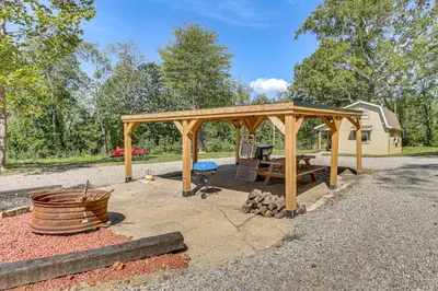 a wooden gazebo with a table and a grill at On 40 Acres Charming Cabin in Zanesville! in Zanesville