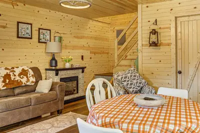 a living room with a couch a table and a fireplace at On 40 Acres Charming Cabin in Zanesville! in Zanesville