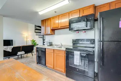 a kitchen with wooden cabinets and a black refrigerator at Unique and Stylish Studio Loft in Huntington! in Huntington