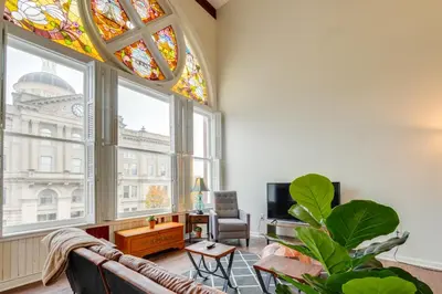 a living room with a couch and stained glass windows at Unique and Stylish Studio Loft in Huntington! in Huntington