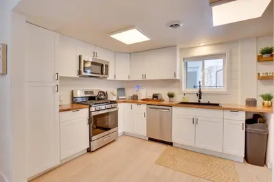 a white kitchen with white cabinets and a window at 3 Mi to Dtwn and YSU Updated Youngstown Home in Youngstown