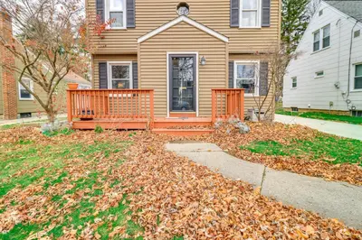 a house with a porch and a pile of leaves at Walk to Adrian College Family Home in Michigan in Adrian