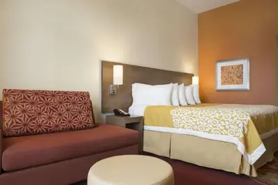 a hotel room with a bed and a chair at Days Inn & Suites by Wyndham Belmont in Belmont