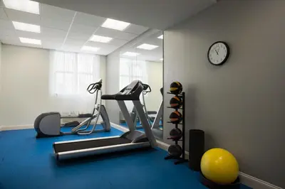 a room with a gym with a treadmill and a clock at Days Inn & Suites by Wyndham Belmont in Belmont