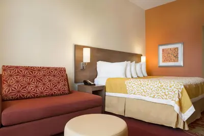 a hotel room with a bed and a chair at Days Inn & Suites by Wyndham Belmont in Belmont