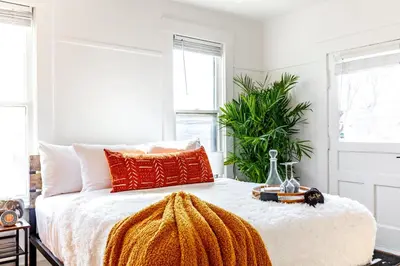 a bedroom with a bed with an orange blanket on it at Jungle House Columbus Downtown Free Parking Sleeps 8 - Near Convention Center & Nationwide Arena - 2BR Luxury Home - Pet Friendly Over 5,800 Five Star Stays in Columbus