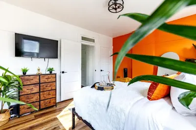 a bedroom with an orange accent wall at Jungle House Columbus Downtown Free Parking Sleeps 8 - Near Convention Center & Nationwide Arena - 2BR Luxury Home - Pet Friendly Over 5,800 Five Star Stays in Columbus