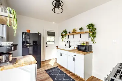 a kitchen with white cabinets and a black refrigerator at Jungle House Columbus Downtown Free Parking Sleeps 8 - Near Convention Center & Nationwide Arena - 2BR Luxury Home - Pet Friendly Over 5,800 Five Star Stays in Columbus