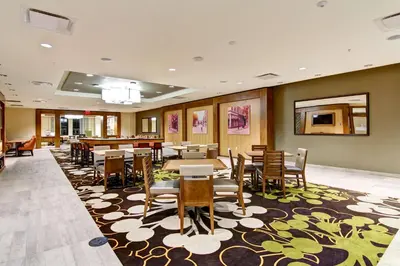 a dining room with tables and chairs on a rug at Homewood Suites by Hilton Cincinnati-Downtown in Cincinnati