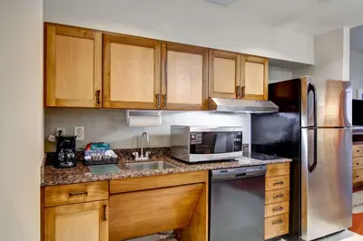 a kitchen with wooden cabinets and a stainless steel refrigerator at Homewood Suites by Hilton Cincinnati-Downtown in Cincinnati