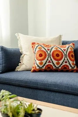 a blue couch with an orange and white pillow on it at Lux Condo Steps to Washington Park - Walk to ALL in Cincinnati