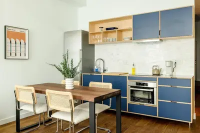 a kitchen with blue cabinets and a wooden table and chairs at Lux Condo Steps to Washington Park - Walk to ALL in Cincinnati