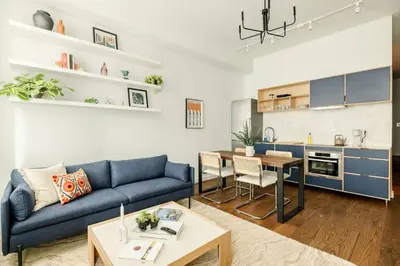 a living room with a blue couch and a kitchen at Lux Condo Steps to Washington Park - Walk to ALL in Cincinnati