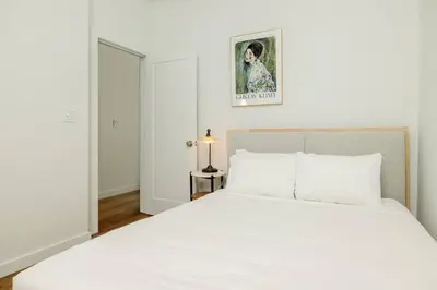 a white bedroom with a large white bed and a lamp at Lux Condo Steps to Washington Park - Walk to ALL in Cincinnati