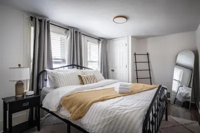a bedroom with a bed with white sheets and a mirror at Walkable to Everywhere in Little Italy- Near CWRU and Cleveland Clinic Main Campus in Cleveland