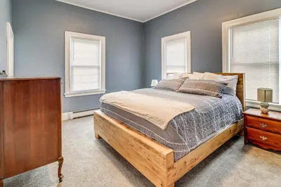 a bedroom with a wooden bed and two windows at 1 Block to Downtown Adrian Spacious Home! in Adrian
