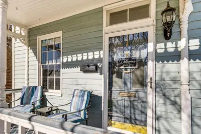 a porch of a house with two chairs and a door at East End River Retreat Dogs Welcome! in Madison