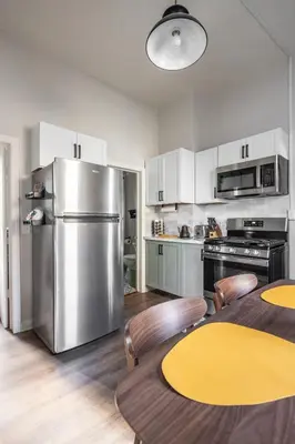 a kitchen with a table and a stainless steel refrigerator at Mid-Century Modern Retreat in Little Italy in Cleveland