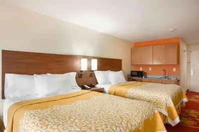 a hotel room with two beds and a kitchen at Days Inn & Suites by Wyndham Caldwell in Caldwell