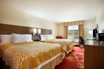 a hotel room with two beds and a television at Days Inn & Suites by Wyndham Caldwell in Caldwell