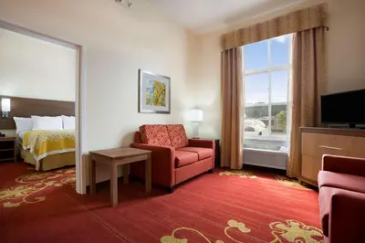 a hotel room with a chair and a bed and a window at Days Inn & Suites by Wyndham Caldwell in Caldwell