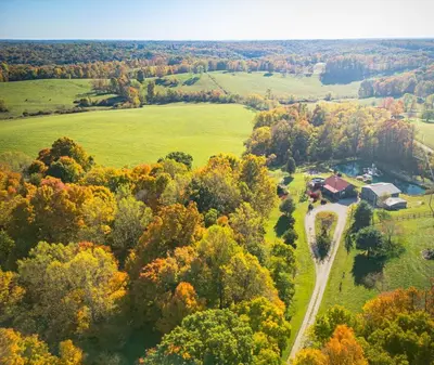 an aerial view of a house in a field with trees at Sunset Cottage Hocking Hills in Rockbridge