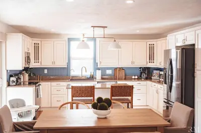 a kitchen with white cabinets and a wooden table at Sunset Cottage Hocking Hills in Rockbridge