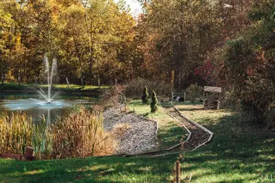 a park with a pond and a fountain and trees at Sunset Cottage Hocking Hills in Rockbridge