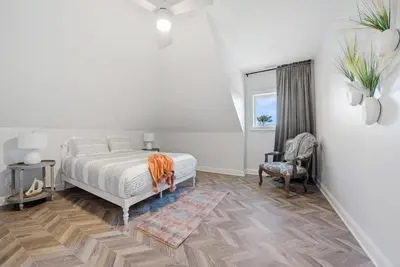 a white bedroom with a bed and a chair at Presidential Suite Sandusky Waterfront Area in Sandusky