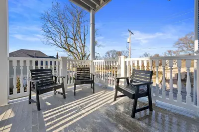 two chairs on a porch with a white fence at Presidential Suite Sandusky Waterfront Area in Sandusky