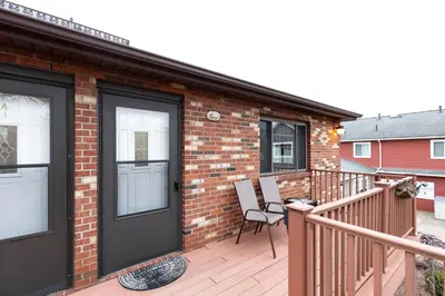 a deck with a black door and chairs on it at Modern Condo Central Huron Boat Basin Area in Huron