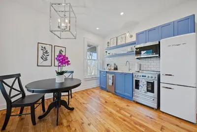 a kitchen with blue cabinets and a table with purple flowers at Luxury Boutique Downtown Private Unit in Sandusky