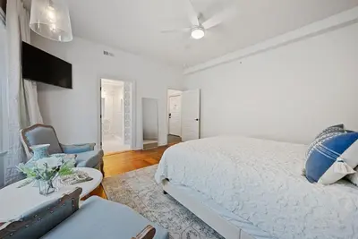 a white bedroom with a bed and a chair at Luxury Boutique Downtown Private Unit in Sandusky