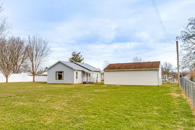 a white house in a yard next to a fence at 17 Mi to Brookville Lake Home with In-Unit Laundry in Connersville