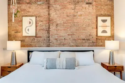 a bedroom with a white bed and a brick wall at Modern Condo in the heart of Over-The-Rhine in Cincinnati