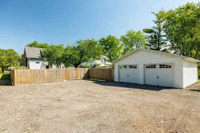 a white garage with a fence in a yard at The Craftsman Uptown - Walk to Shops & Eats in Perrysburg