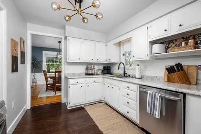 a kitchen with white cabinets and a dining room at The Craftsman Uptown - Walk to Shops & Eats in Perrysburg