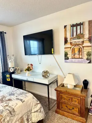a bedroom with a desk with a tv on a wall at Comfortable King Bedroom within A HOME WITH HOSTS in Columbus