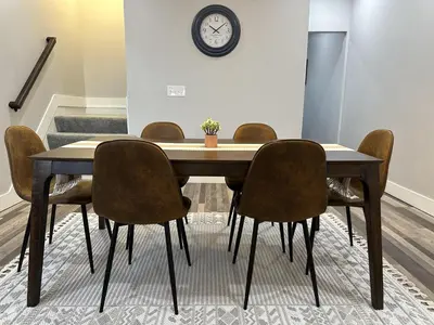 a dining room table with chairs and a clock on the wall at Lovely 2BR Near Downtown Area in Columbus