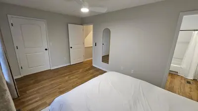 a bedroom with white walls and wood floors and a mirror at North Columbus Townhouse - Central, Updated, Fireplace in Columbus