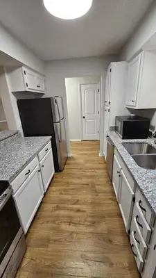 a kitchen with white cabinets and a wooden floor at North Columbus Townhouse - Central, Updated, Fireplace in Columbus