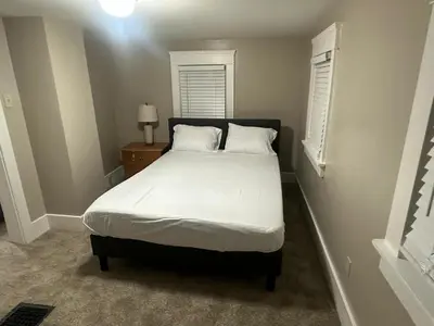 a bedroom with a bed with white sheets and a window at The Perazim in Akron
