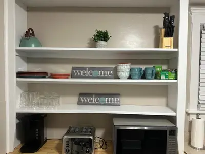 a kitchen shelf with a microwave and dishes on it at The Perazim in Akron