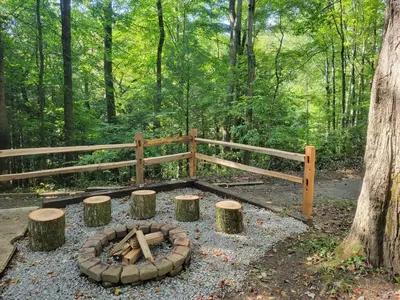 a fire pit in the woods next to a fence at Mountainside Cabin, Secluded, Hot Tub, Lake Accessible in Rockbridge
