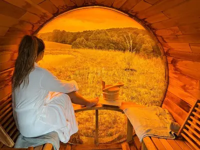 a woman sitting at a table looking out of a round window at Nature Mystique Retreat 3 Bedroom Moroccan Cabin in Creola