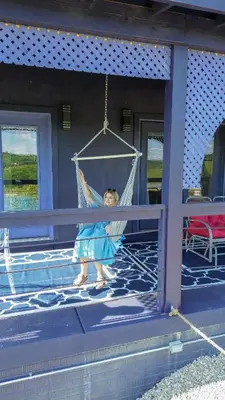 a little girl in a swing on a house at Nature Mystique Retreat 3 Bedroom Moroccan Cabin in Creola