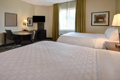 a hotel room with two beds and a desk at Candlewood Suites St Clairsville Wheeling Area by IHG in Saint Clairsville