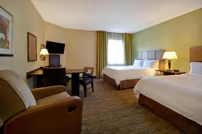 a hotel room with two beds and a desk at Candlewood Suites St Clairsville Wheeling Area by IHG in Saint Clairsville